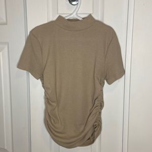 Beige shirt with straps on the side.